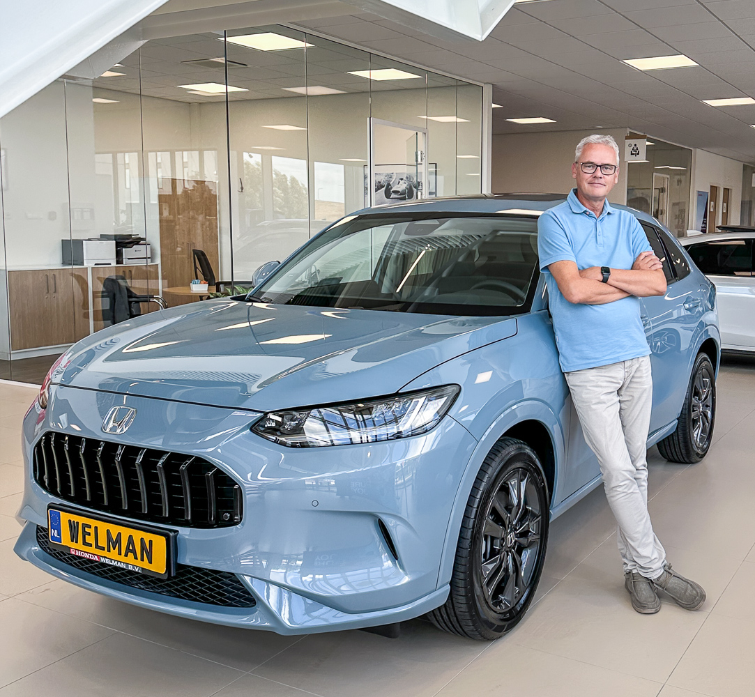 Robert Gort, fotograaf en marketeer bij Honda Welman, naast een Honda in de showroom